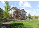 This landscaped backyard has a stone patio with seating, a lawn, a stone retaining wall and mature trees at 1240 Starglow Pl, Highlands Ranch, CO 80126