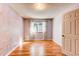 A bedroom featuring hardwood floors, a window with decorative curtains, and neutral-colored walls at 5894 S Oak St, Littleton, CO 80127