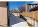 A side yard with a wooden fence is partially snow-covered on a sunny day at 5894 S Oak St, Littleton, CO 80127