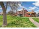 Backyard view of a charming red home featuring a lush green lawn and inviting outdoor space at 8424 Everett Way # A, Arvada, CO 80005
