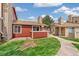 Exterior showcasing a red home with a stone chimney, lush lawn, and a sidewalk at 8424 Everett Way # A, Arvada, CO 80005