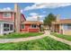 Exterior daytime shot of the red home featuring a stone chimney, manicured lawn, and walkway at 8424 Everett Way # A, Arvada, CO 80005
