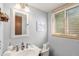 Bathroom featuring a white sink, framed mirror, wood blinds, and natural light at 7622 E Nassau Ave, Denver, CO 80237