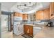 Cozy kitchen featuring wood cabinets, laminate countertops, and white appliances at 7622 E Nassau Ave, Denver, CO 80237