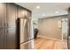 Open kitchen featuring stainless steel refrigerator, dark cabinetry, and wood floors, flowing into living area at 3180 Mowry Pl, Westminster, CO 80031