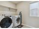 Clean laundry room with modern washer and dryer, shelving, and a window for natural light at 9807 Rosalee Peak St, Littleton, CO 80125