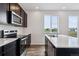 Bright kitchen with stainless steel appliances, dark cabinets, and a central island overlooking the backyard at 14412 Heritage Dr, Mead, CO 80504