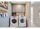 Well-organized laundry room with front-load washer and dryer, upper cabinets, and tasteful decorations at 14412 Heritage Dr, Mead, CO 80504
