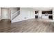 Spacious living room showcasing stylish floors, staircase, and an adjacent modern kitchen with sleek, dark cabinetry at 14412 Heritage Dr, Mead, CO 80504