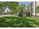 Well-manicured lawn in front of a multi-story building with mature trees and a view of a street at 3465 S Poplar St # 305, Denver, CO 80224