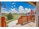 Inviting porch with wood railings, showcasing a view of a green lawn and blue sky with an American flag waving at 4959 Rocky View Pt, Castle Rock, CO 80108