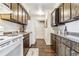 Galley kitchen with dark cabinets, white appliances, and a view into the living space at 3339 S Monaco Pkwy # A, Denver, CO 80222