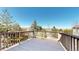 Balcony deck with wooden rails and a wooden deck overlooks landscaping and neighborhood trees under a sunny, blue sky at 1977 Champions Cir, Castle Rock, CO 80104