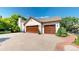 A house with a wide driveway leads to a two-car garage with wooden garage doors, set against a backdrop of lush greenery at 1977 Champions Cir, Castle Rock, CO 80104