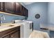 Well-lit laundry room features front loading washer and dryer and plenty of cabinets for ample storage solutions at 6746 S Biloxi Ct, Aurora, CO 80016