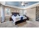 Spacious main bedroom with large bed, massage chair, barn door leading to bathroom, and tray ceiling with fan at 6746 S Biloxi Ct, Aurora, CO 80016