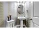 Stylish half-bathroom with pedestal sink, decorative mirror, and elegant wallpaper at 6746 S Biloxi Ct, Aurora, CO 80016