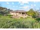 Scenic backyard view featuring a stone patio, lush greenery, mature trees, and well-maintained landscaping at 4305 Easley Rd, Golden, CO 80403