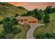A beautiful aerial view of a brick house nestled in a lush, green landscape with mountain views at 5808 Crestbrook Cir, Morrison, CO 80465