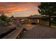 Exterior view of backyard patio and home featuring stone details and brick exterior under colorful sunset at 5808 Crestbrook Cir, Morrison, CO 80465