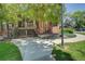 Brick building entrance with staircase and sidewalk under the shade of a mature tree at 2181 S Troy Way # 103, Aurora, CO 80014