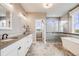 Bright bathroom featuring a dual sink vanity, soaking tub, glass-enclosed shower, and scenic outdoor views from the window at 8750 Red Primrose St, Franktown, CO 80116