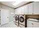 Well-lit laundry room features modern washer and dryer, white cabinets, and stylish tile floor at 8750 Red Primrose St, Franktown, CO 80116