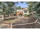 Wide shot of the house showing fresh garden, mature trees, and wooden deck with stairs at 5814 Cole Way, Arvada, CO 80004