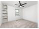 Spare bedroom featuring a ceiling fan, built-in shelving, a window, and neutral carpet at 5814 Cole Way, Arvada, CO 80004
