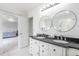 Bathroom featuring double sinks with granite countertops, decorative mirrors, and access to the bedroom at 20604 E 38Th Pl, Denver, CO 80249