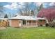 Large backyard of brick home, featuring a patio, green lawn and a pink blossoming tree at 8307 E Lehigh Dr, Denver, CO 80237