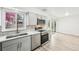 Modern kitchen with gray cabinets, stainless steel appliances, quartz countertops, and hexagon backsplash at 8307 E Lehigh Dr, Denver, CO 80237