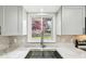Updated kitchen features a stainless sink and mosaic backsplash at 8307 E Lehigh Dr, Denver, CO 80237