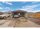 The metal carport accommodates two vehicles and includes shelving for extra storage at 3670 Ivanhoe St, Denver, CO 80207