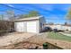 Two car detached garage with white doors and siding, located in a well maintained backyard at 8441 Mcdougal St, Denver, CO 80229
