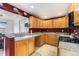 Well-lit kitchen with wood cabinets, granite countertops, tile flooring, and access to the adjacent dining area at 8441 Mcdougal St, Denver, CO 80229