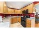 Traditional kitchen with wood cabinets, granite countertops, black appliances, and tile flooring at 8441 Mcdougal St, Denver, CO 80229
