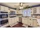 Well-lit kitchen featuring white cabinets, stainless steel appliances, tile backsplash, and wood flooring at 7729 Beverly Blvd, Castle Pines, CO 80108