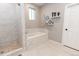 Luxurious bathroom showcasing a separate shower and soaking tub with marble-style tile at 16301 Hudson Rd, Hudson, CO 80642