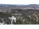 Picturesque aerial view of a cabin nestled among snow-covered trees with mountain backdrop at 5525 S Twin Spruce Dr, Evergreen, CO 80439