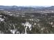 Scenic aerial of a small home nestled in snow covered trees with a majestic mountain backdrop at 5525 S Twin Spruce Dr, Evergreen, CO 80439