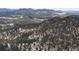 Aerial view of a winding road snaking through a dense forest, leading towards mountains at 5525 S Twin Spruce Dr, Evergreen, CO 80439