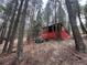 Cabin exterior surrounded by tall trees with red foundation showing underneath at 5525 S Twin Spruce Dr, Evergreen, CO 80439