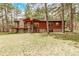 Charming wood-sided home featuring a stone chimney and a spacious deck surrounded by lush trees at 1150 Fremont Dr, Larkspur, CO 80118