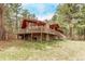 Spacious home with a large wooden deck and stone foundation, surrounded by a serene wooded landscape at 1150 Fremont Dr, Larkspur, CO 80118