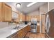 This kitchen features stainless steel appliances, light wood cabinets, and a double sink with an exterior view at 1150 Fremont Dr, Larkspur, CO 80118