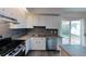 Updated kitchen features white cabinetry, stainless steel appliances, and dark backsplash at 230 S 22Nd Ave, Brighton, CO 80601