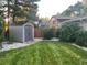 Well-maintained backyard with a gray storage shed, lush green lawn, river rock, and mature trees and landscaping at 3052 S Gilpin St, Denver, CO 80210