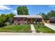Charming brick house with green lawn, mature trees, and welcoming yellow front door at 1741 W 55Th Pl, Denver, CO 80221