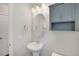 Powder room with pedestal sink, oval mirror, and a storage cabinet above the toilet at 8211 Monte Vista Cir, Littleton, CO 80125